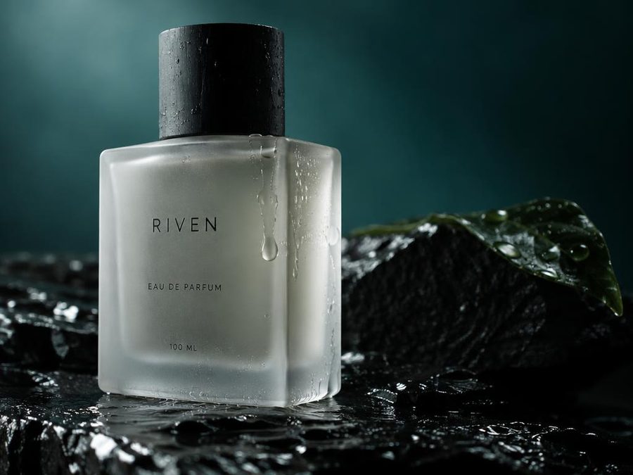 A frosted glass perfume bottle on wet black slate